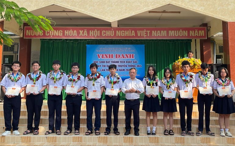 Thầy Huỳnh Tấn Châu (giữa), Hiệu trưởng nhà trường trao hoa, quà vinh danh 11 em đạt HCV tại kỳ thi Olympic truyền thống 30/4 lần thứ XXVIII năm 2024. Ảnh: HIẾU TRUNG